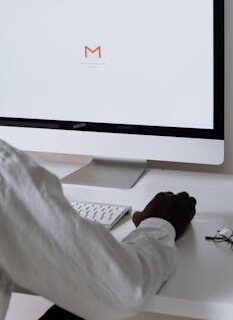 A professional in an office setting checking emails on a desktop computer with a clean workspace.